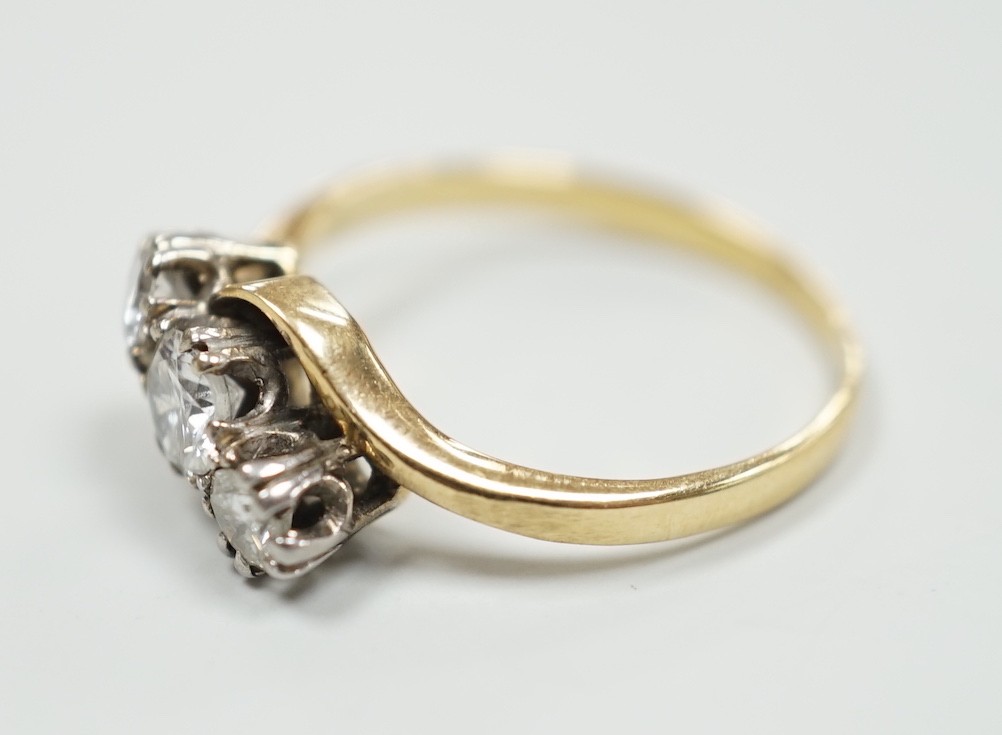 A yellow metal and three stone diamond set crossover ring, size K, gross weight 2.1 grams